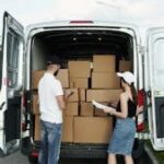 Delivery workers organizing boxes from a van on a sunny day.