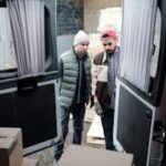 Two delivery workers load parcels into a van, focusing on efficiency and teamwork.